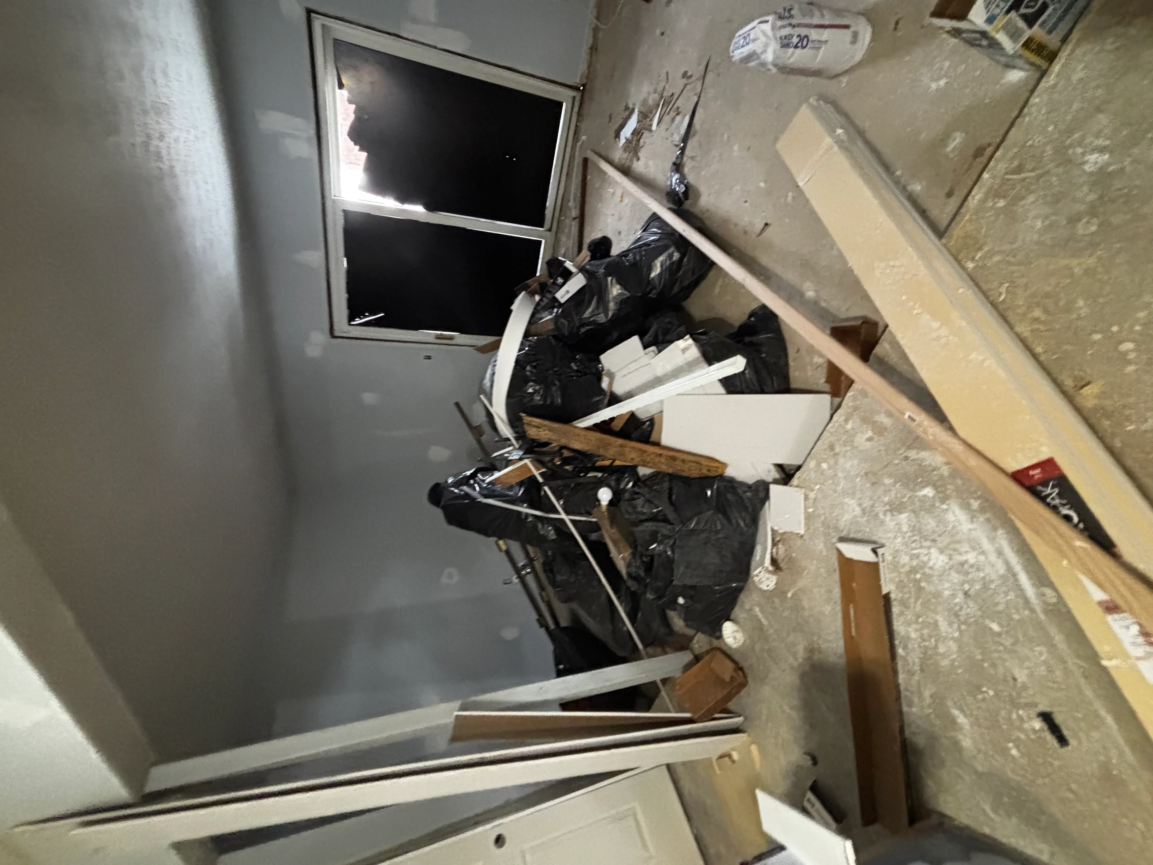 Interior demolition project showing removed drywall, framing materials, and debris staged for removal