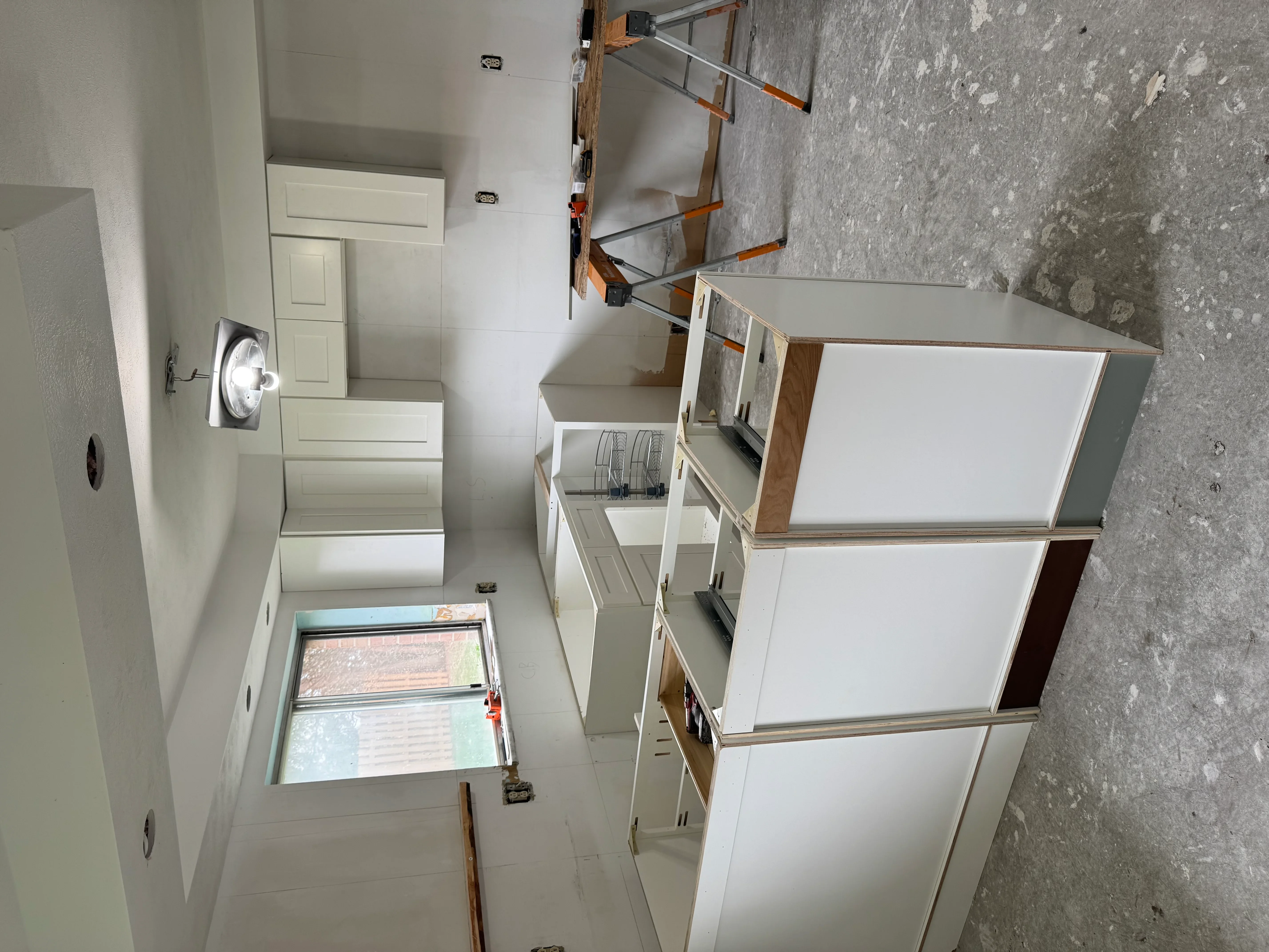 White kitchen cabinets installed with wood trim and stainless hardware in renovation project