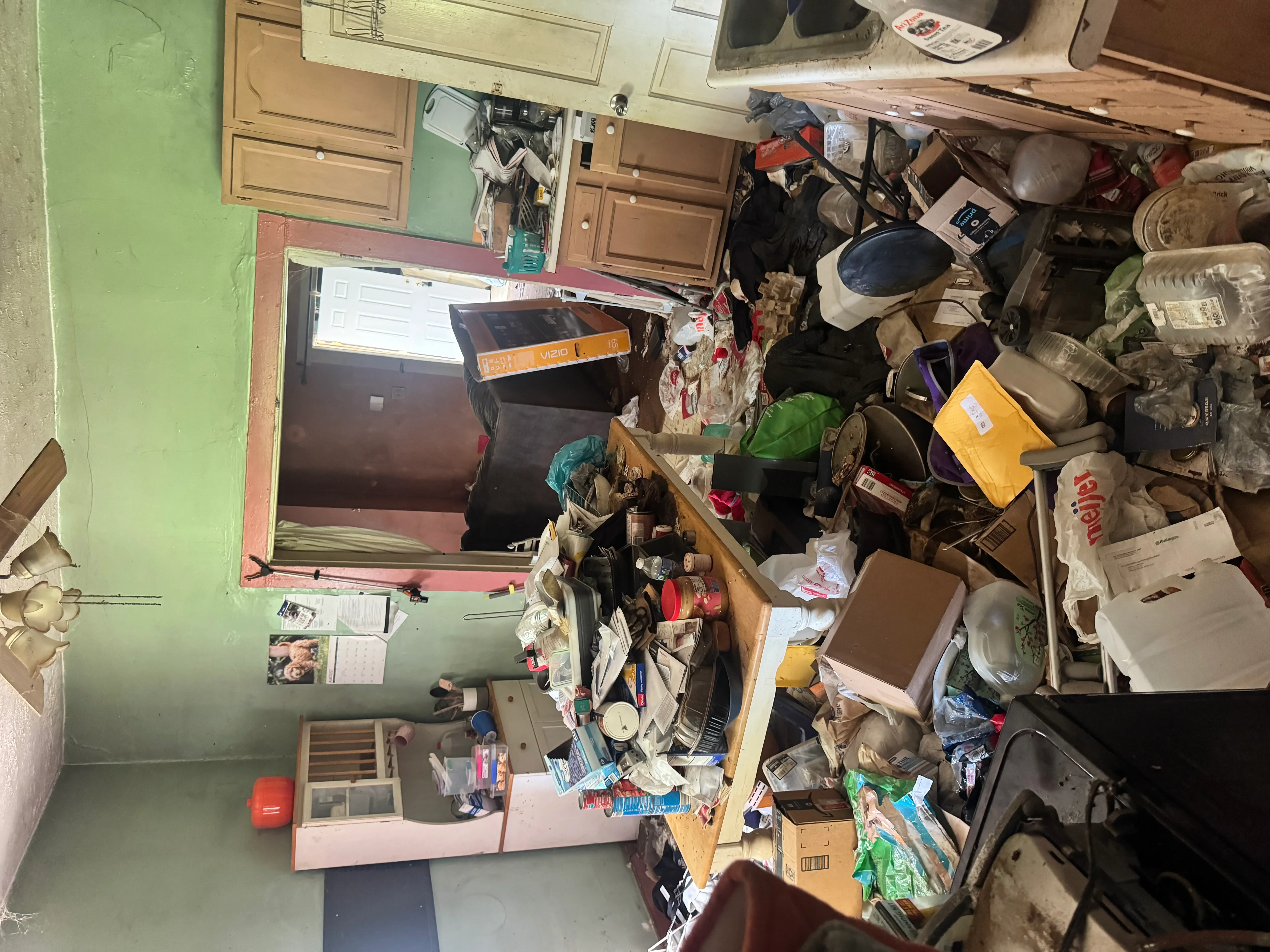 Before photo of cluttered garage with accumulated boxes, tools, and household items