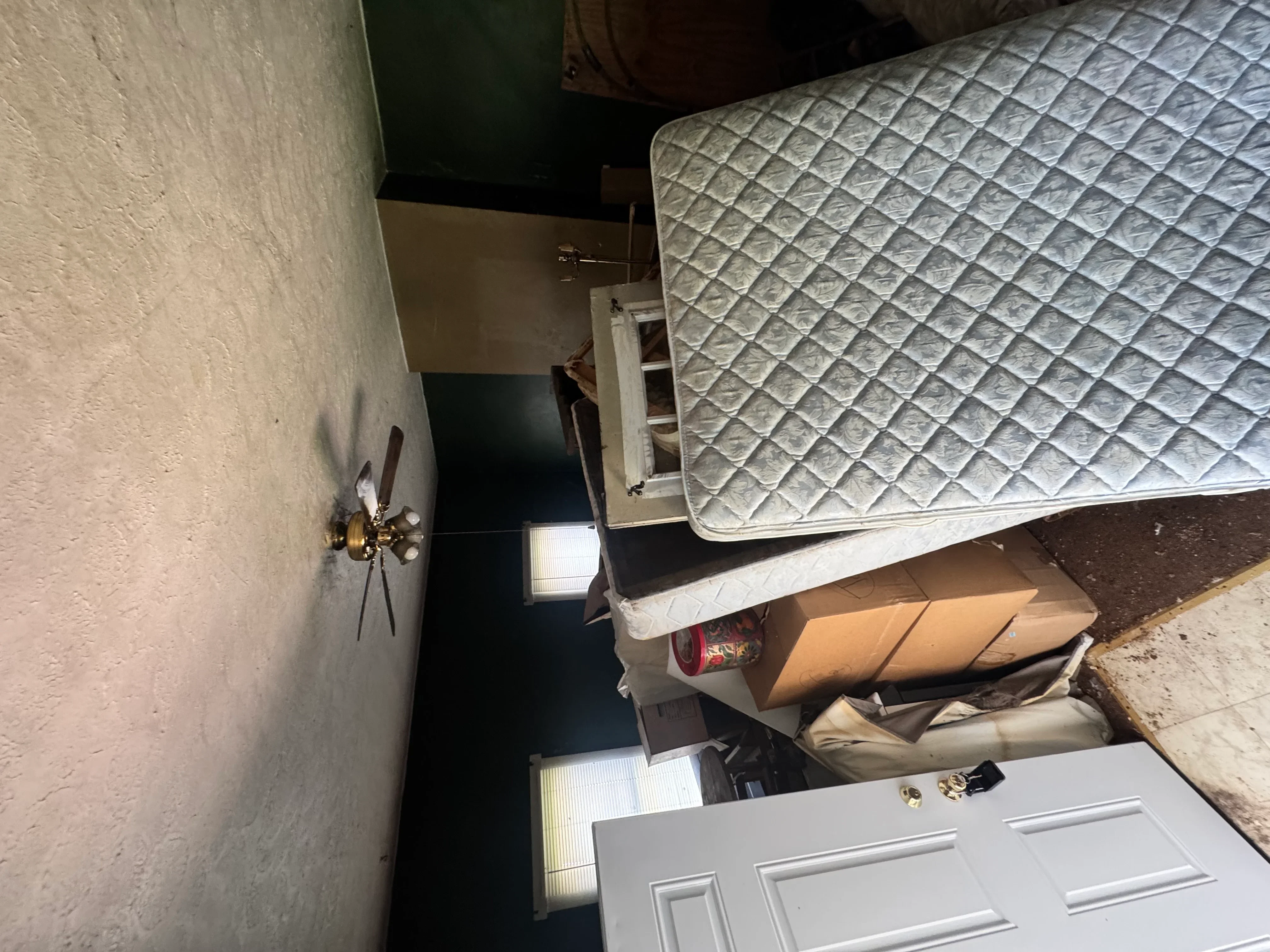 Bedroom renovation in progress with new door, textured drywall, and brass wall fixture
