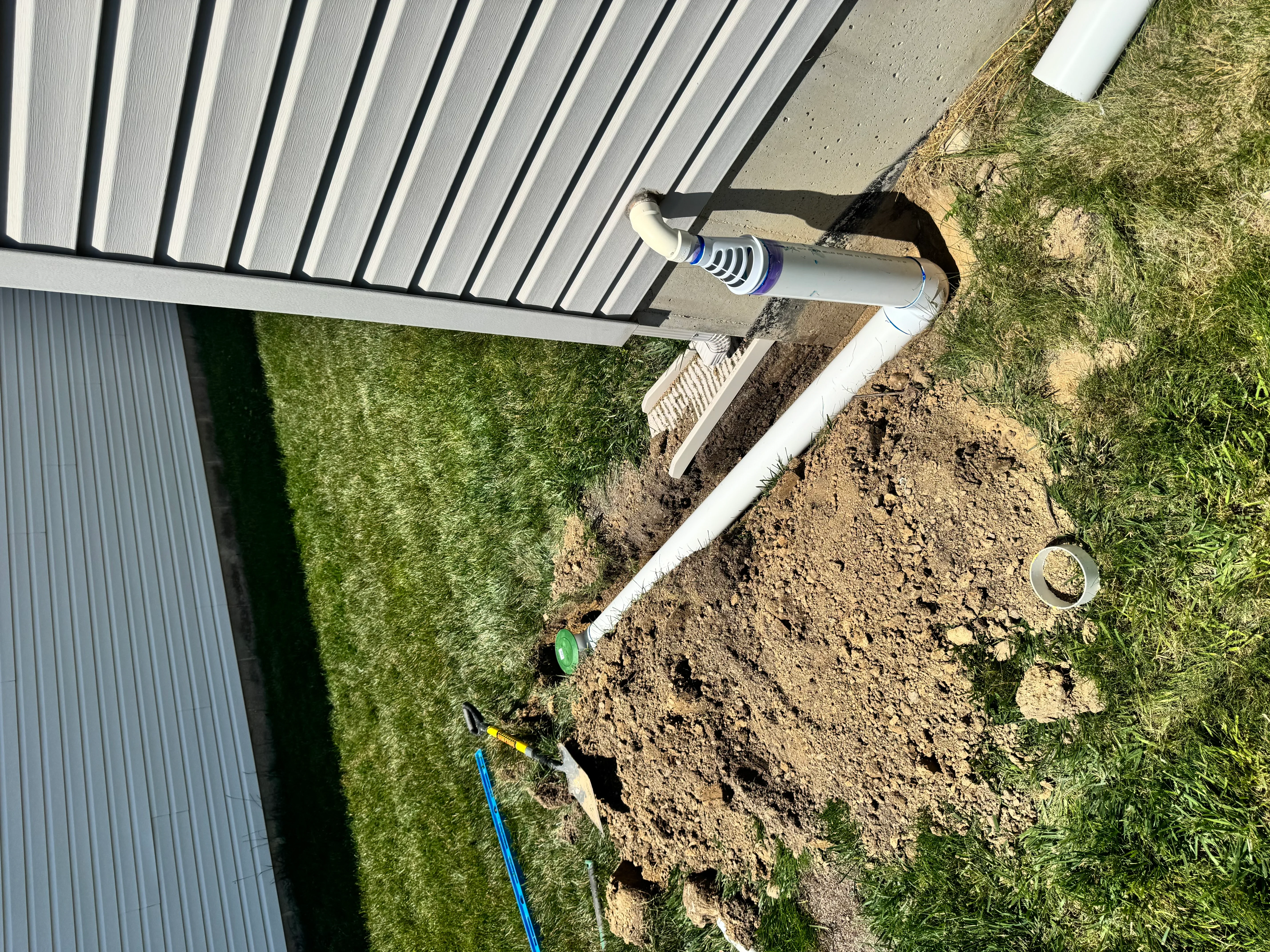 White aluminum gutter system with downspout and underground drainage pipe installation